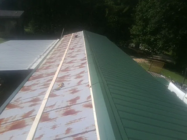 Old rusted panels beside newly installed green metal roofing — Wind Damage Roof Repair by Roofing Brothers in Nanuet