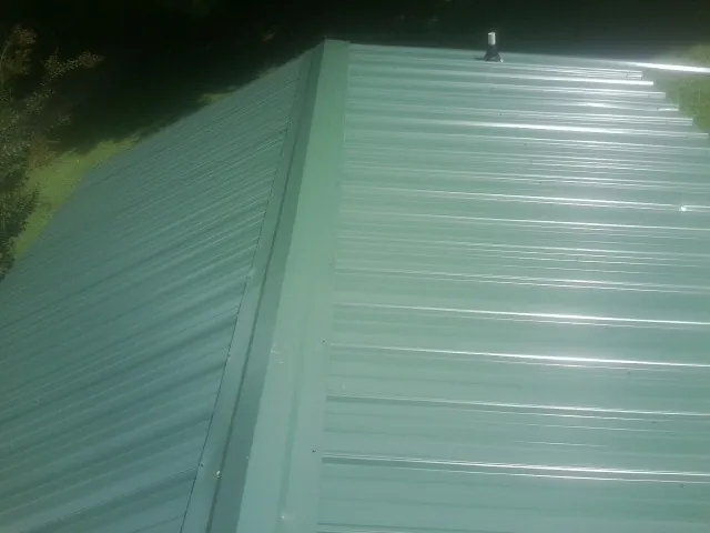 New green metal panels meeting at the ridge of a roof — Flat Roof Repair work by our crew in Nanuet