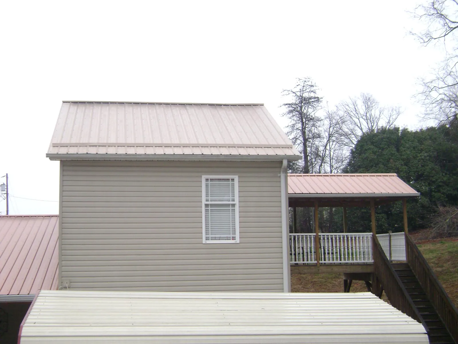 Tan metal roofs on a two story addition and attached porch, from a Roof Replacement job in Nanuet
