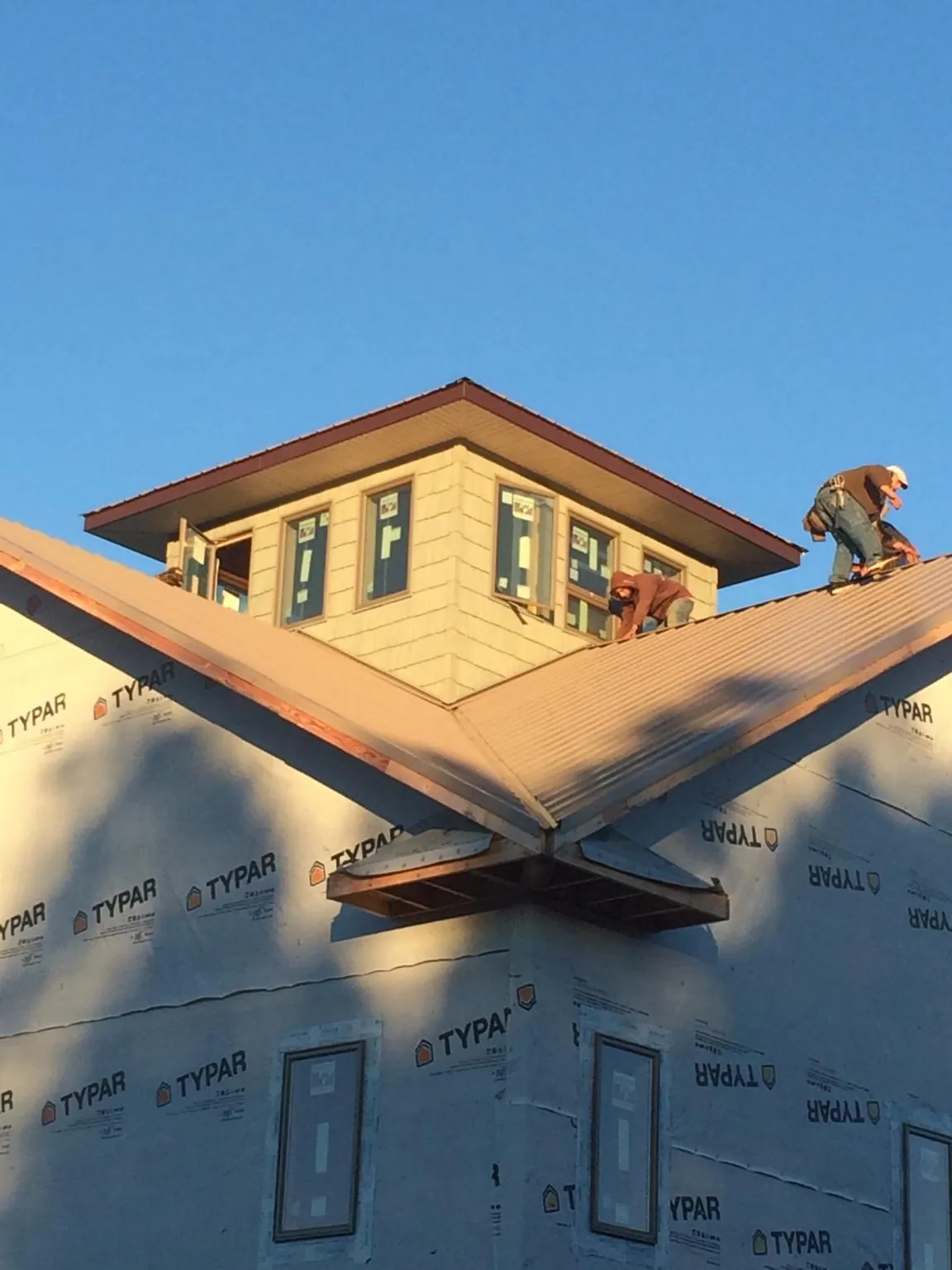 Roofers working around a rooftop cupola on a new metal roof at sunset — Roof Waterproofing in Nanuet by Roofing Brothers